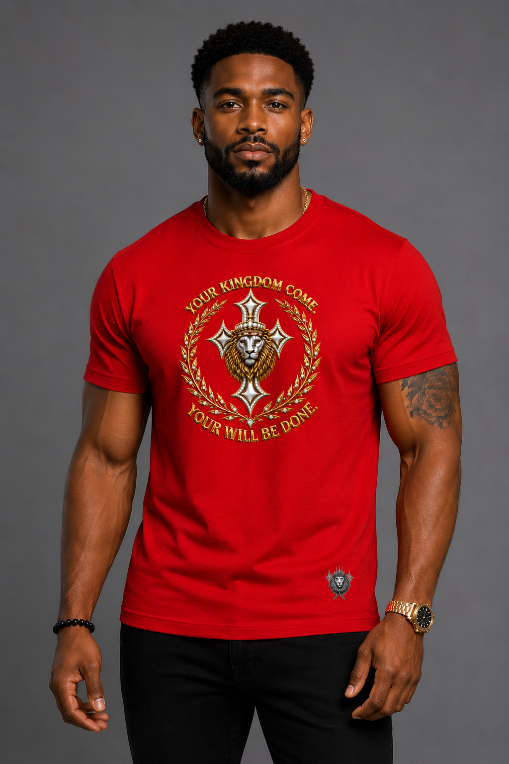 A man wearing a bright red crewneck t-shirt with a gold and silver military-style emblem and the text 'YOUR KINGDOM COME' and 'YOUR WILL BE DONE'.