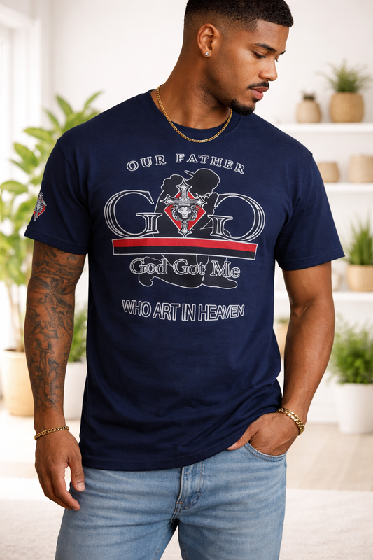 Man wearing a navy blue t-shirt with a graphic design and text, standing in a room with plants and shelves.