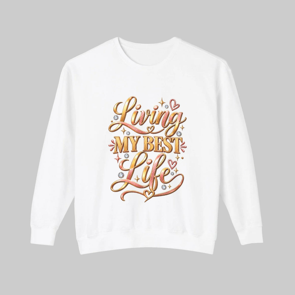 A white crewneck sweatshirt featuring a colorful graphic on the front that reads 'Living My Best Life' in stylized orange, pink, and gold lettering with small heart and sparkle accents, displayed on a clean white background.
