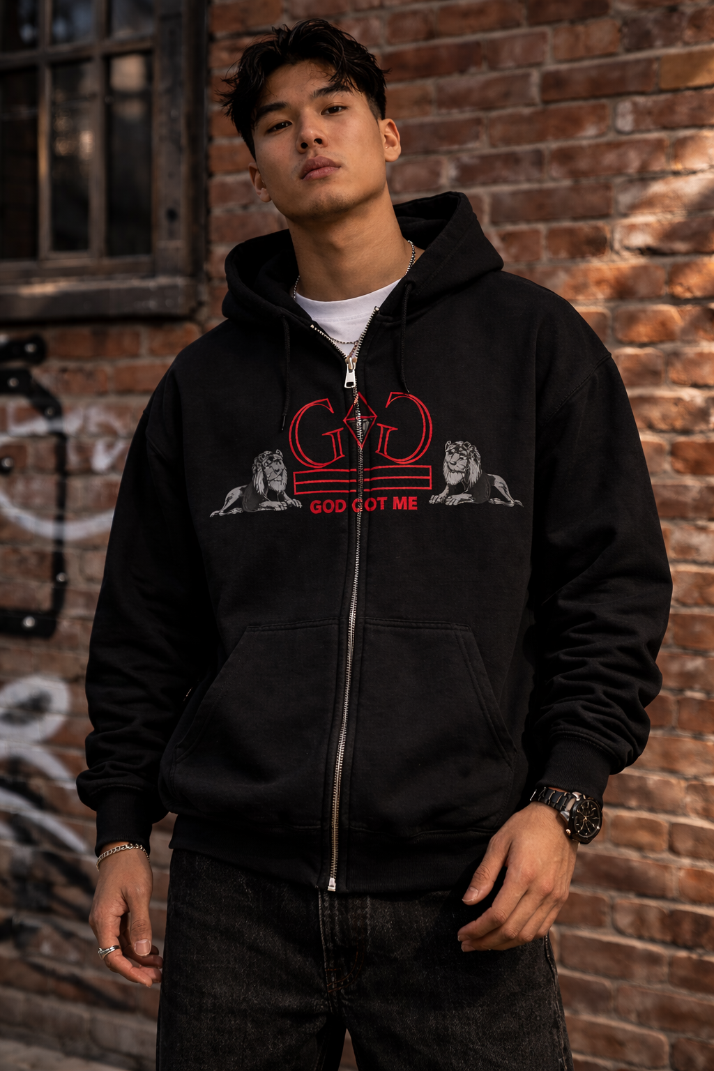 Person wearing a black hoodie with a graphic design in front of a brick wall.