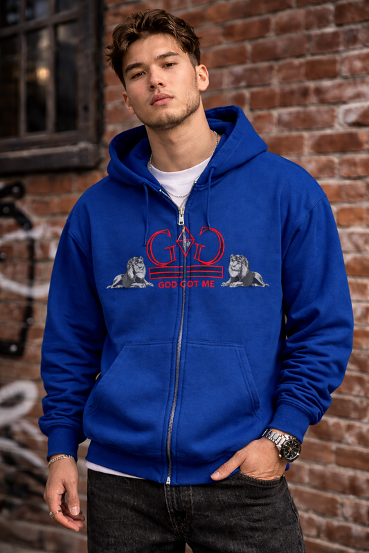 Man wearing a blue hoodie with a logo and text against a brick wall.