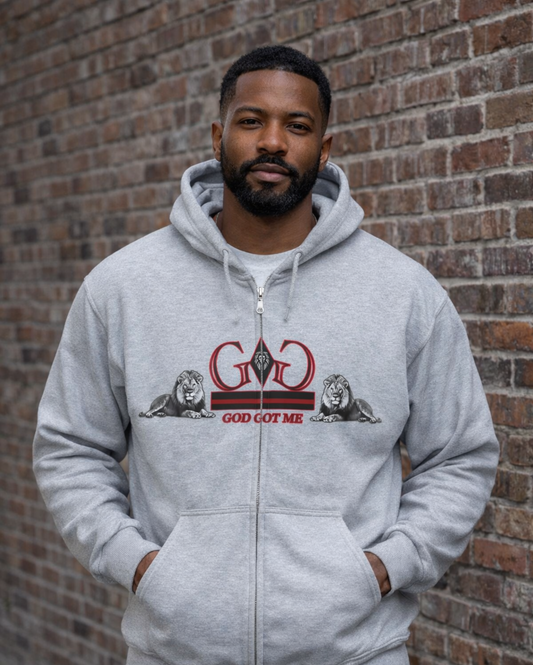 Man wearing a gray hoodie with a graphic design in front of a brick wall
